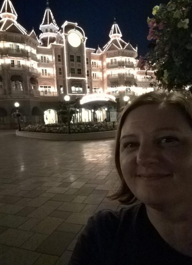 travel agent in the foreground of the Disneyland Hotel in Paris lit up at night